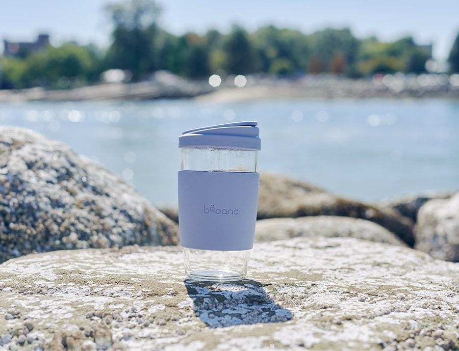 eco-friendly reusable glass cup by the beach on a sunny day