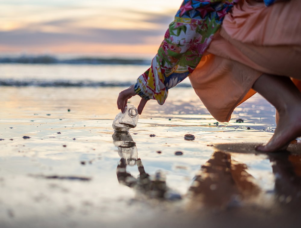 volunteer collecting plastic bottles and cups and cups from the ocean